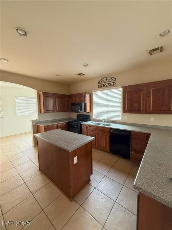 kitchen with light tile patterned flooring, a sink, a center island, visible vents, and black appliances