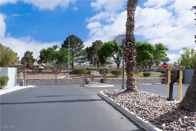 view of road with a gate, a gated entry, traffic signs, and curbs