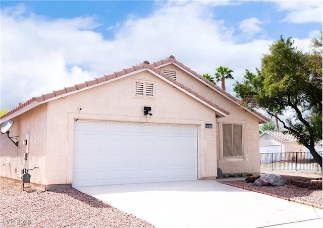 view of front of property with a tiled roof, an attached garage, concrete driveway, and stucco siding