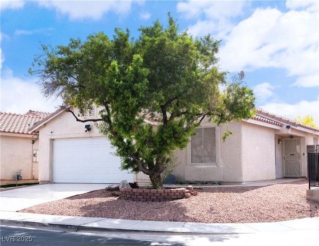 view of front of home featuring stucco siding, an attached garage, driveway, and a tiled roof