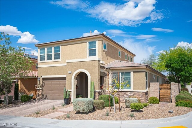 2198 Maderno St, Henderson, NV 89044 - view of front of home with a garage, fence, stone siding, stucco siding, and concrete driveway