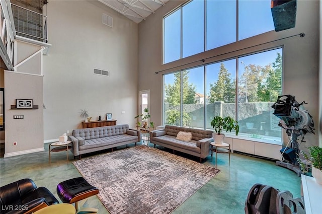 living room featuring plenty of natural light, concrete floors, and a towering ceiling