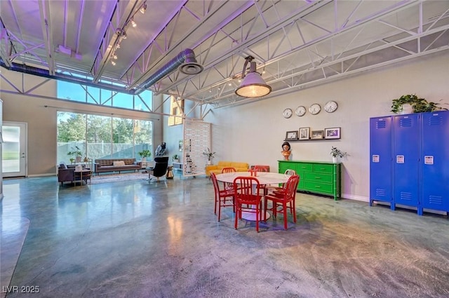 dining room with finished concrete flooring, baseboards, and a towering ceiling