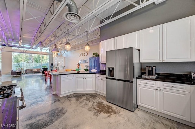 kitchen with appliances with stainless steel finishes, dark countertops, white cabinets, a peninsula, and concrete floors