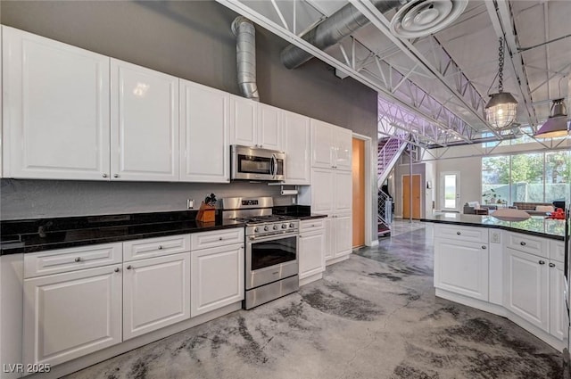 kitchen featuring white cabinets, dark countertops, appliances with stainless steel finishes, concrete floors, and pendant lighting