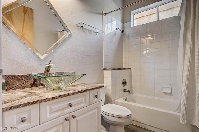 full bath featuring vanity, a textured wall, shower / bath combination with curtain, and toilet