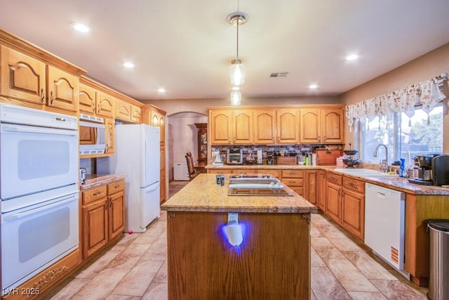 5180 N Dapple Gray Rd, Las Vegas, NV 89149 - kitchen featuring white appliances, a sink, arched walkways, a center island, and decorative backsplash