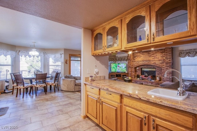 5180 N Dapple Gray Rd, Las Vegas, NV 89149 - kitchen featuring a sink, light stone countertops, glass insert cabinets, and a textured ceiling