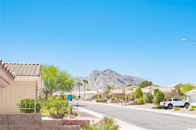 view of road with street lighting, a residential view, a mountain view, and sidewalks