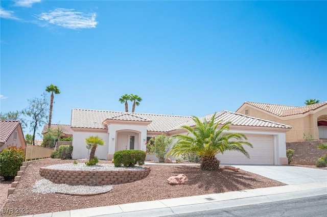 mediterranean / spanish-style house with an attached garage, concrete driveway, stucco siding, and a tile roof