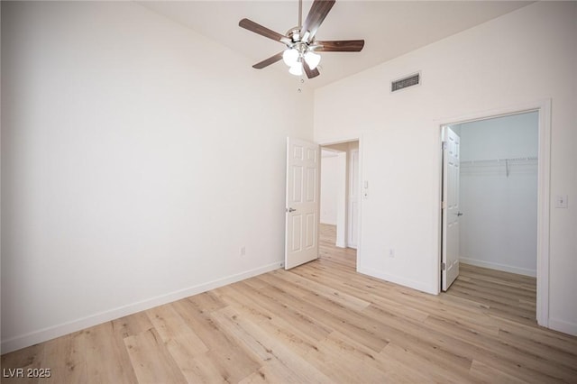 unfurnished bedroom with baseboards, visible vents, high vaulted ceiling, and light wood-style floors