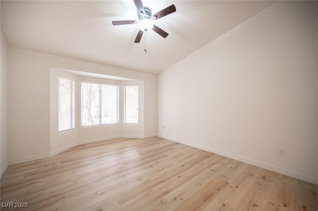 spare room featuring baseboards, vaulted ceiling, ceiling fan, and light wood-type flooring
