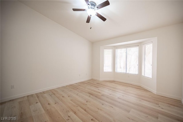 empty room featuring baseboards, a ceiling fan, light wood-type flooring, and lofted ceiling