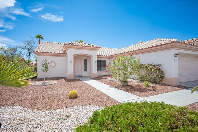 mediterranean / spanish-style home with a garage, stucco siding, and a tiled roof
