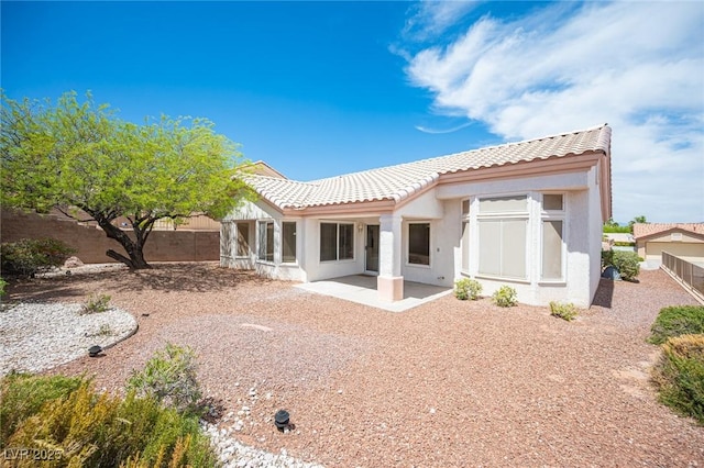 rear view of property featuring a tiled roof, a fenced backyard, a patio area, and stucco siding