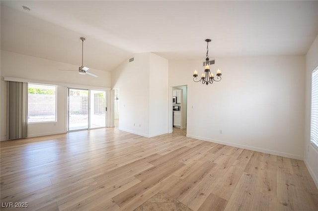 spare room featuring visible vents, light wood-style floors, baseboards, ceiling fan with notable chandelier, and vaulted ceiling