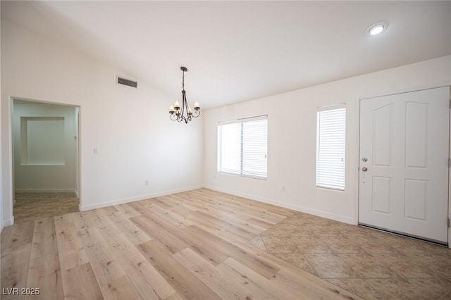 entrance foyer with visible vents, lofted ceiling, baseboards, light wood-type flooring, and a chandelier