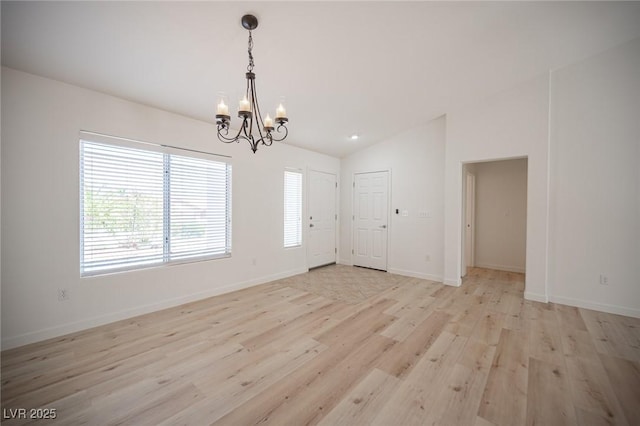 unfurnished dining area with light wood-style floors, baseboards, lofted ceiling, and a notable chandelier