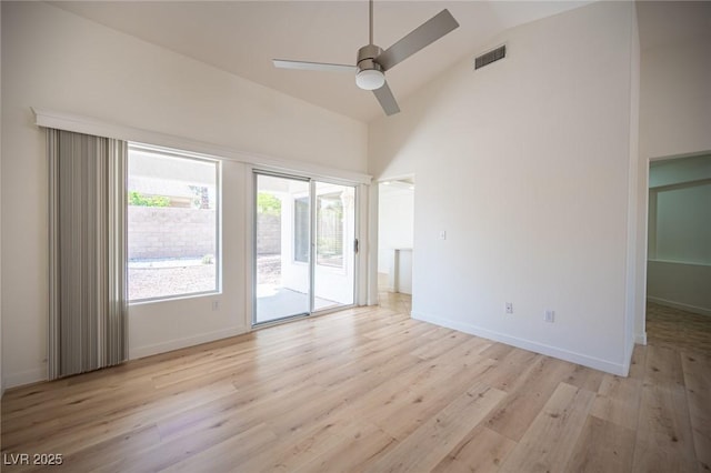 empty room featuring a ceiling fan, high vaulted ceiling, visible vents, and light wood-style flooring