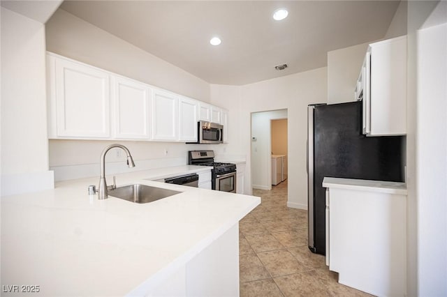 kitchen with appliances with stainless steel finishes, a sink, separate washer and dryer, recessed lighting, and white cabinetry