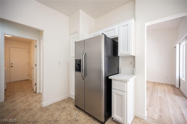 kitchen featuring white cabinets, baseboards, stainless steel fridge with ice dispenser, and light countertops