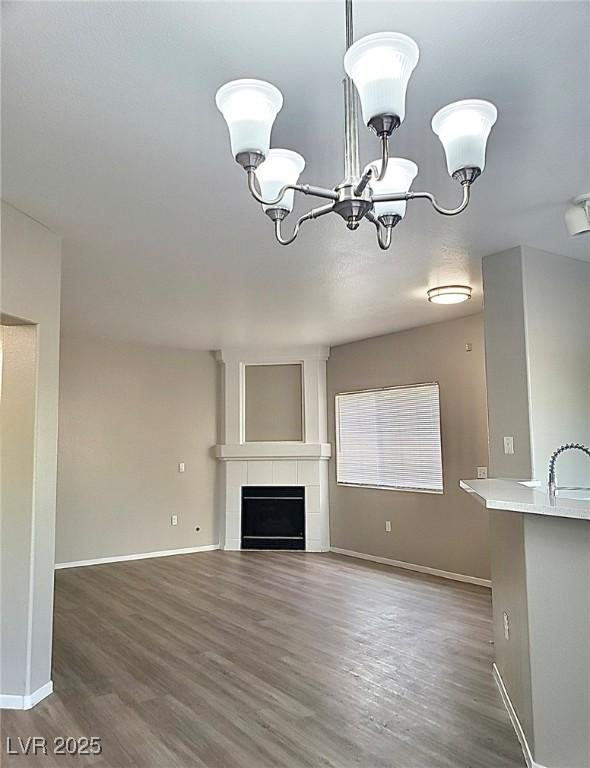 unfurnished living room featuring baseboards, a notable chandelier, and wood finished floors