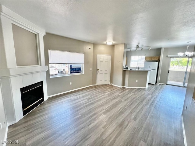 1881 W Alexander Rd Unit 1128, North Las Vegas, NV 89032 - unfurnished living room featuring a chandelier, a textured ceiling, a tiled fireplace, and wood finished floors