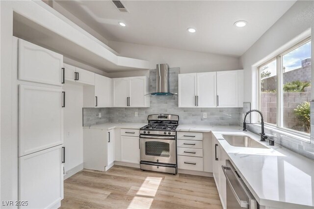 7413 Red Eagle St, Las Vegas, NV 89131 - kitchen featuring wall chimney exhaust hood, stainless steel appliances, a sink, light wood-type flooring, and decorative backsplash