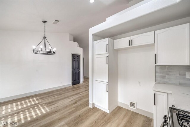 7413 Red Eagle St, Las Vegas, NV 89131 - kitchen with white cabinetry, light wood finished floors, a chandelier, light countertops, and decorative light fixtures