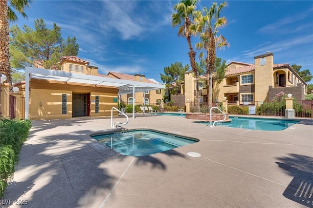 community pool with a hot tub, a patio, and fence