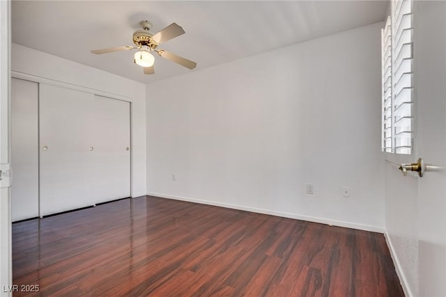 unfurnished bedroom with a ceiling fan, baseboards, dark wood finished floors, and a closet