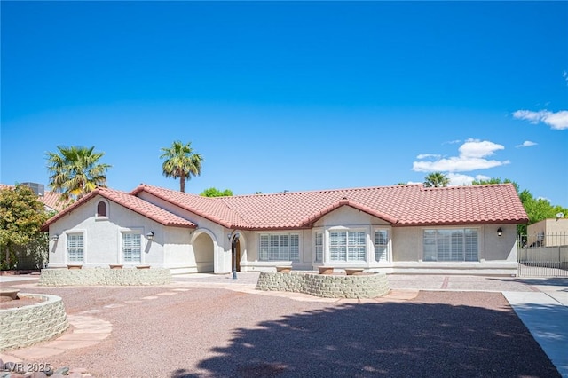 mediterranean / spanish house featuring a tiled roof, fence, and stucco siding