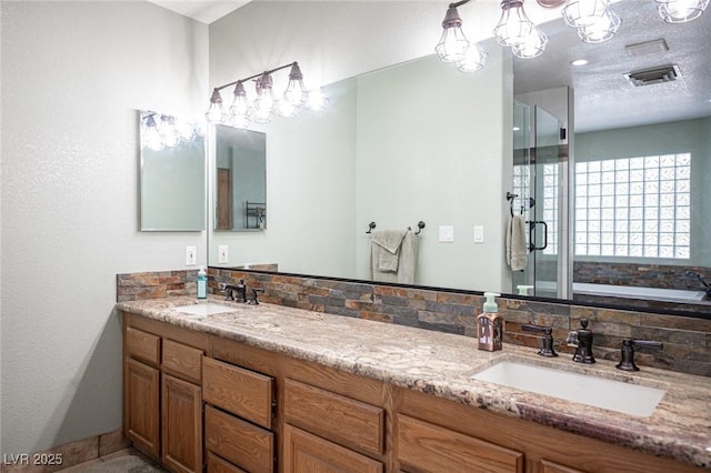 full bathroom featuring double vanity, visible vents, a shower stall, and a sink