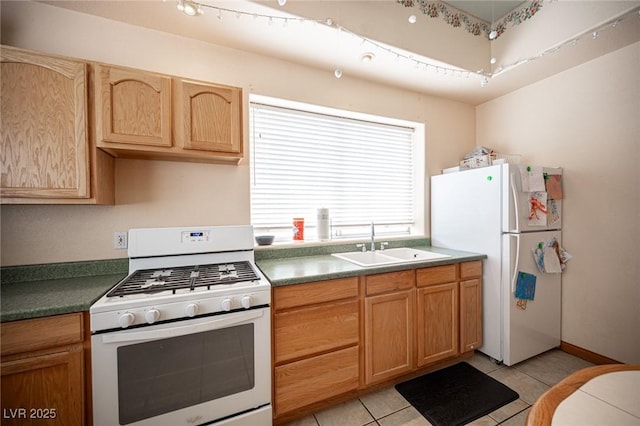 kitchen with a sink, dark countertops, light tile patterned flooring, and white appliances