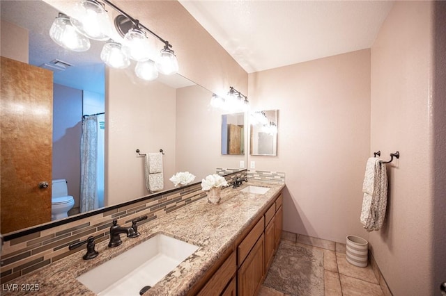 full bathroom with a sink, baseboards, toilet, and double vanity