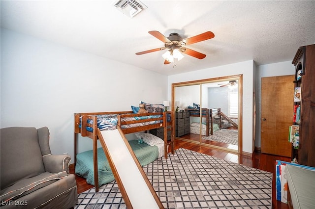 bedroom with ceiling fan, a closet, wood finished floors, and visible vents