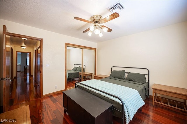 bedroom with baseboards, visible vents, dark wood finished floors, and a closet