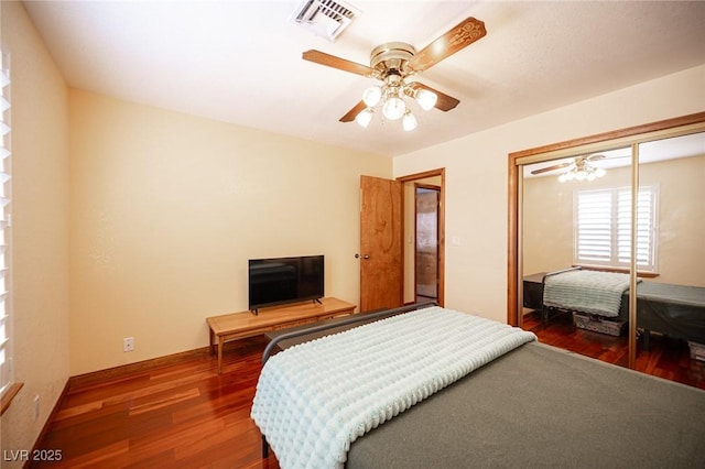 bedroom with visible vents, a closet, wood finished floors, baseboards, and ceiling fan