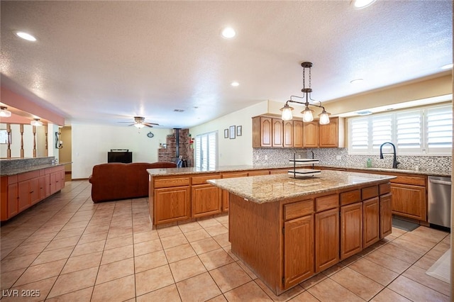 kitchen featuring a sink, dishwasher, a center island, a ceiling fan, and light tile patterned floors