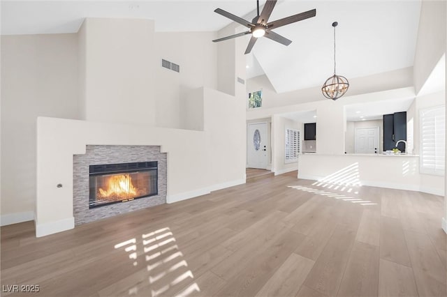 6961 Emerald Springs Ln, Las Vegas, NV 89113 - unfurnished living room with high vaulted ceiling, a stone fireplace, light wood finished floors, baseboards, and ceiling fan