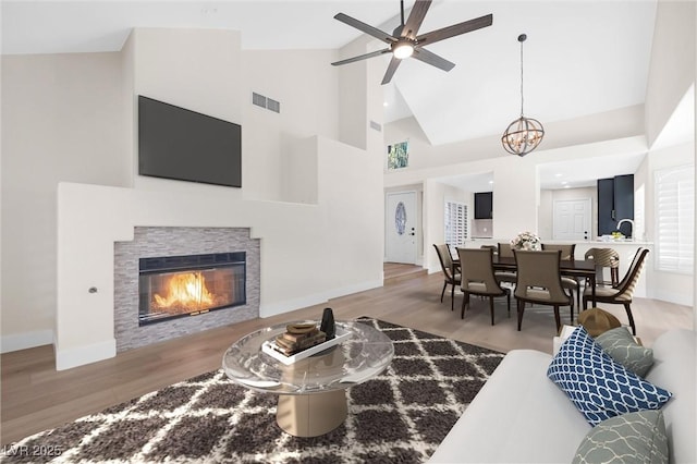 6961 Emerald Springs Ln, Las Vegas, NV 89113 - living area with wood finished floors, high vaulted ceiling, a tiled fireplace, baseboards, and a ceiling fan