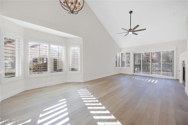 6961 Emerald Springs Ln, Las Vegas, NV 89113 - unfurnished living room featuring high vaulted ceiling, light wood-style floors, ceiling fan, a chandelier, and baseboards