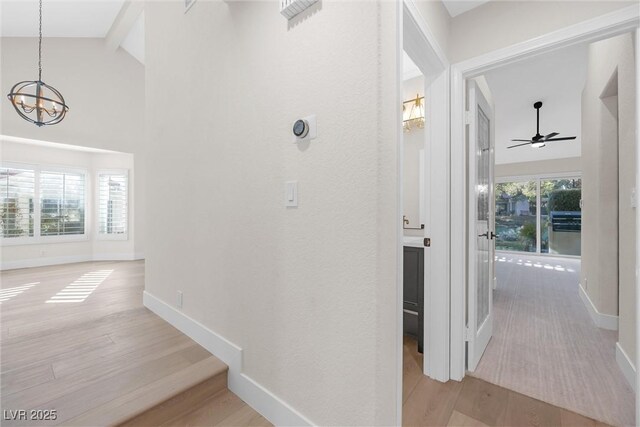 6961 Emerald Springs Ln, Las Vegas, NV 89113 - hallway featuring light wood finished floors, a chandelier, baseboards, and high vaulted ceiling