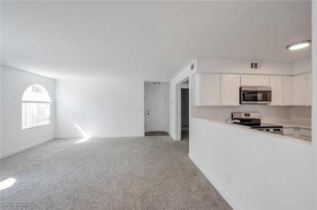 kitchen featuring white cabinets, light carpet, light countertops, stainless steel appliances, and visible vents