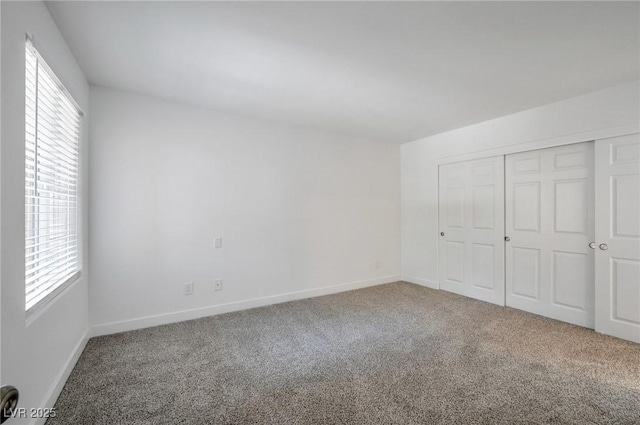 unfurnished bedroom featuring baseboards, multiple windows, and carpet