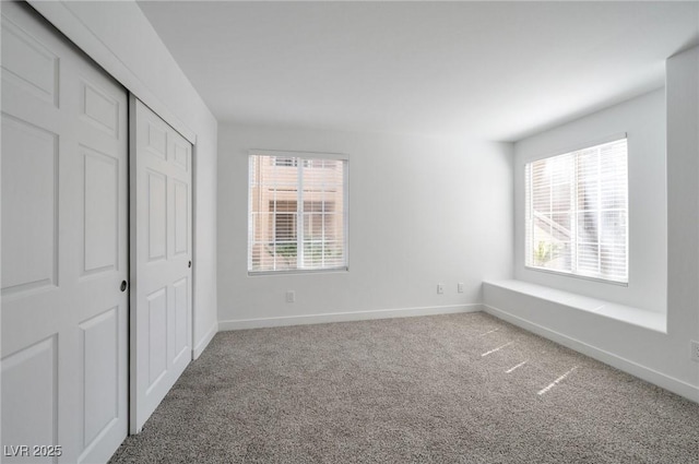 unfurnished bedroom featuring baseboards, multiple windows, carpet, and a closet
