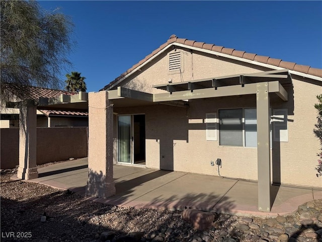rear view of property with a patio area, stucco siding, a tile roof, and fence