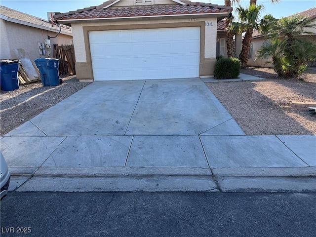 view of front of house with a tiled roof, an attached garage, driveway, and stucco siding