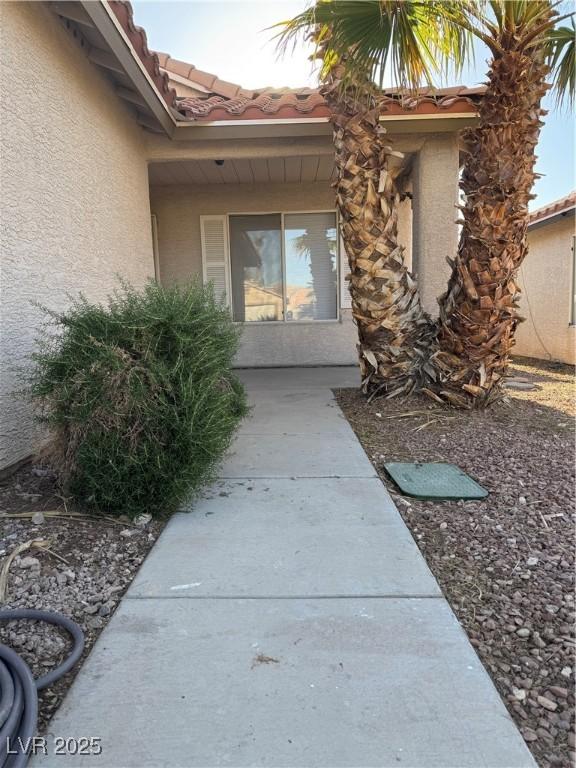doorway to property with stucco siding and a tiled roof