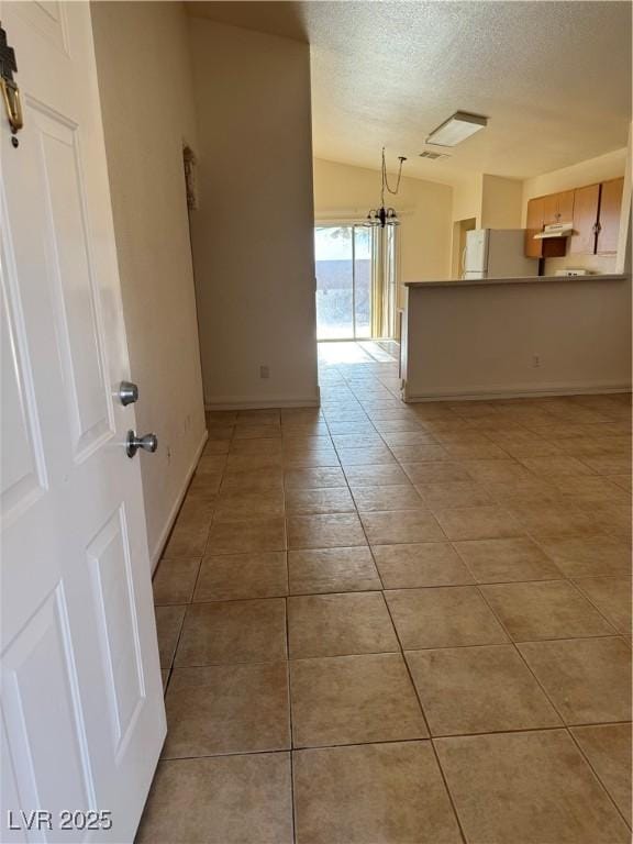 unfurnished room with baseboards, a textured ceiling, and light tile patterned floors